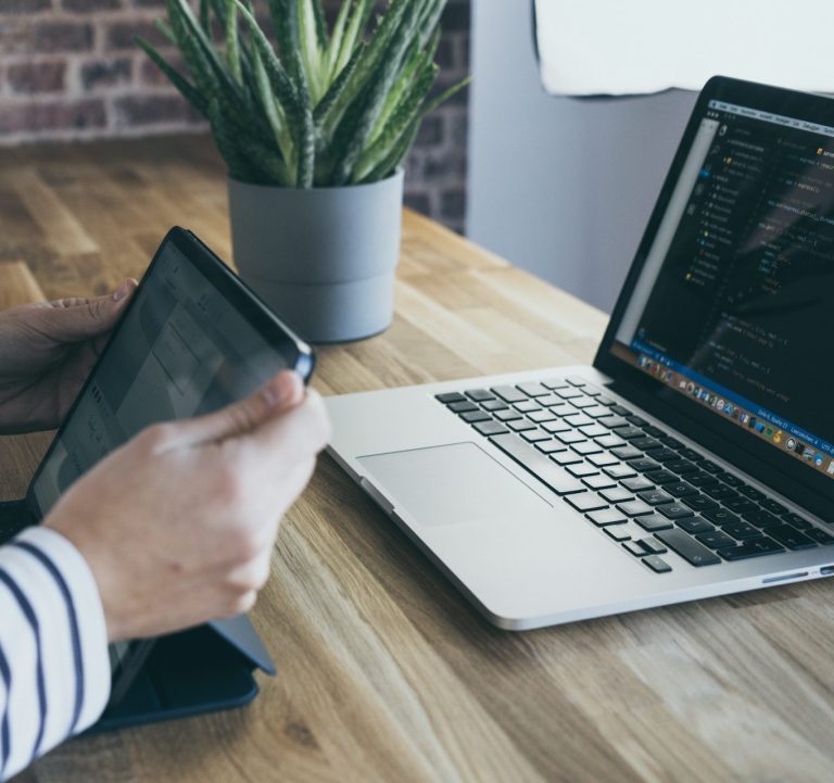 person holding a small laptop in front of a larger laptop